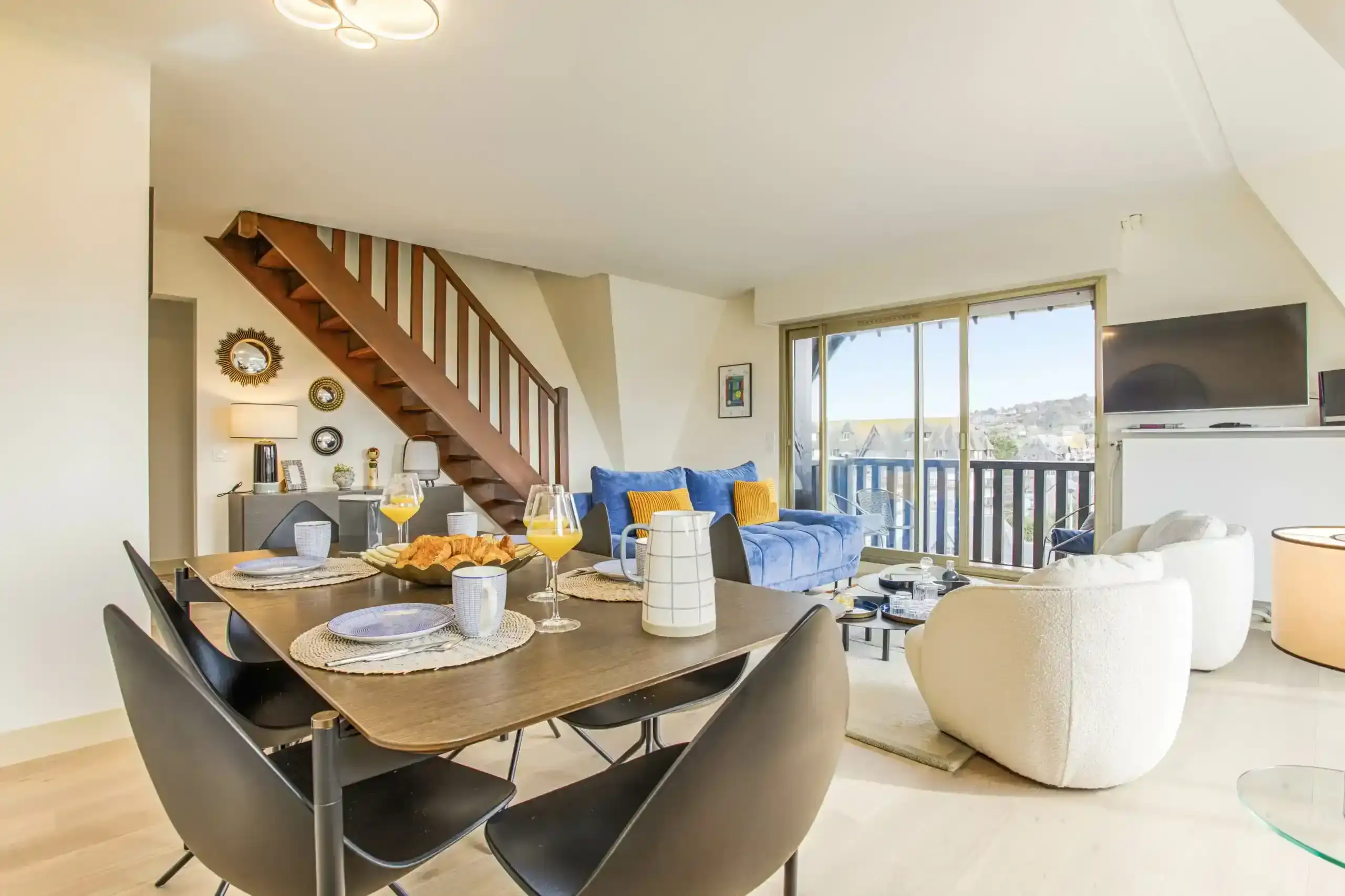 Appartement-ciel-mer-salle-a-manger-vue-balcon Salle à manger moderne avec table dressée et accès au balcon dans l’appartement Ciel et Mer à Deauville