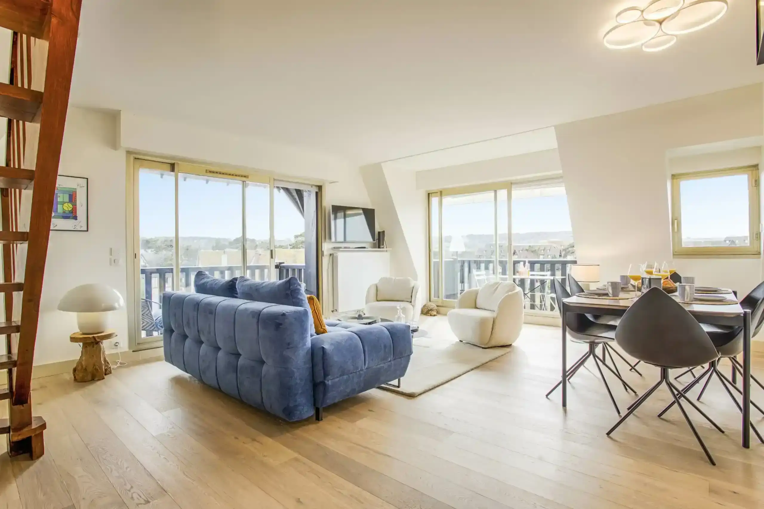 Appartement-ciel-mer-salon-duplex-lumineux Salon en duplex avec canapé bleu et salle à manger dans l’appartement Ciel et Mer à Deauville