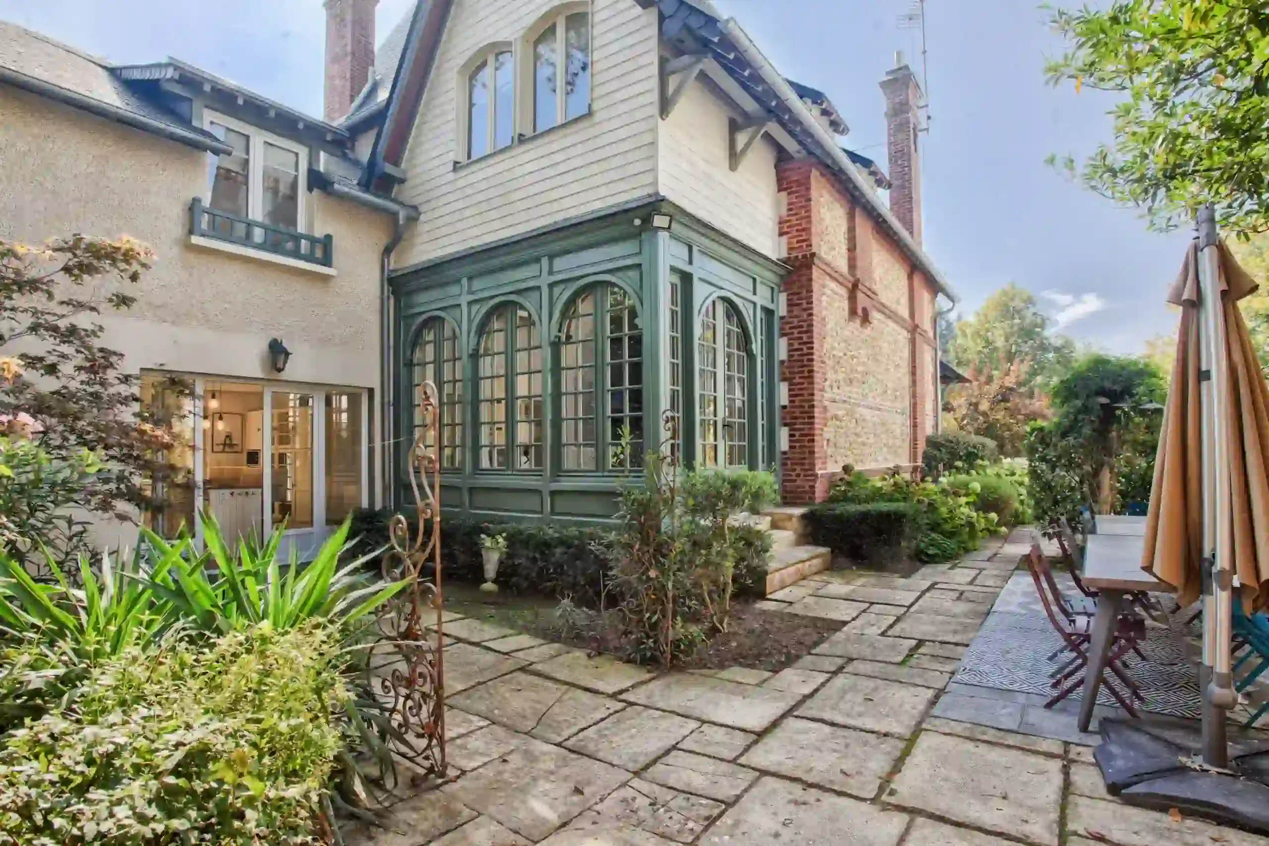 Villa-athena-exterieur-jardin-terrasse-deauville Extérieur de la Villa Athena avec terrasse aménagée et jardin arboré à Deauville