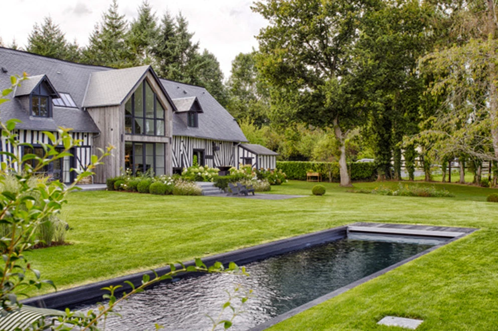 Villa de standing avec piscine et jardin paysager à Deauville Vue extérieure d’une villa normande haut de gamme avec bardage bois, jardin arboré et piscine moderne, à Deauville