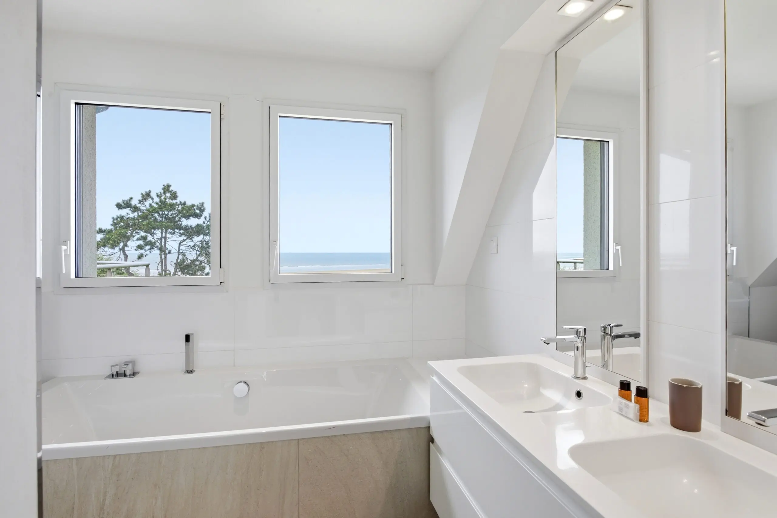 Salle de bains lumineuse avec baignoire et vue sur la mer — Appartement 56 à Deauville, service conciergerie luxe all‑inclusive.