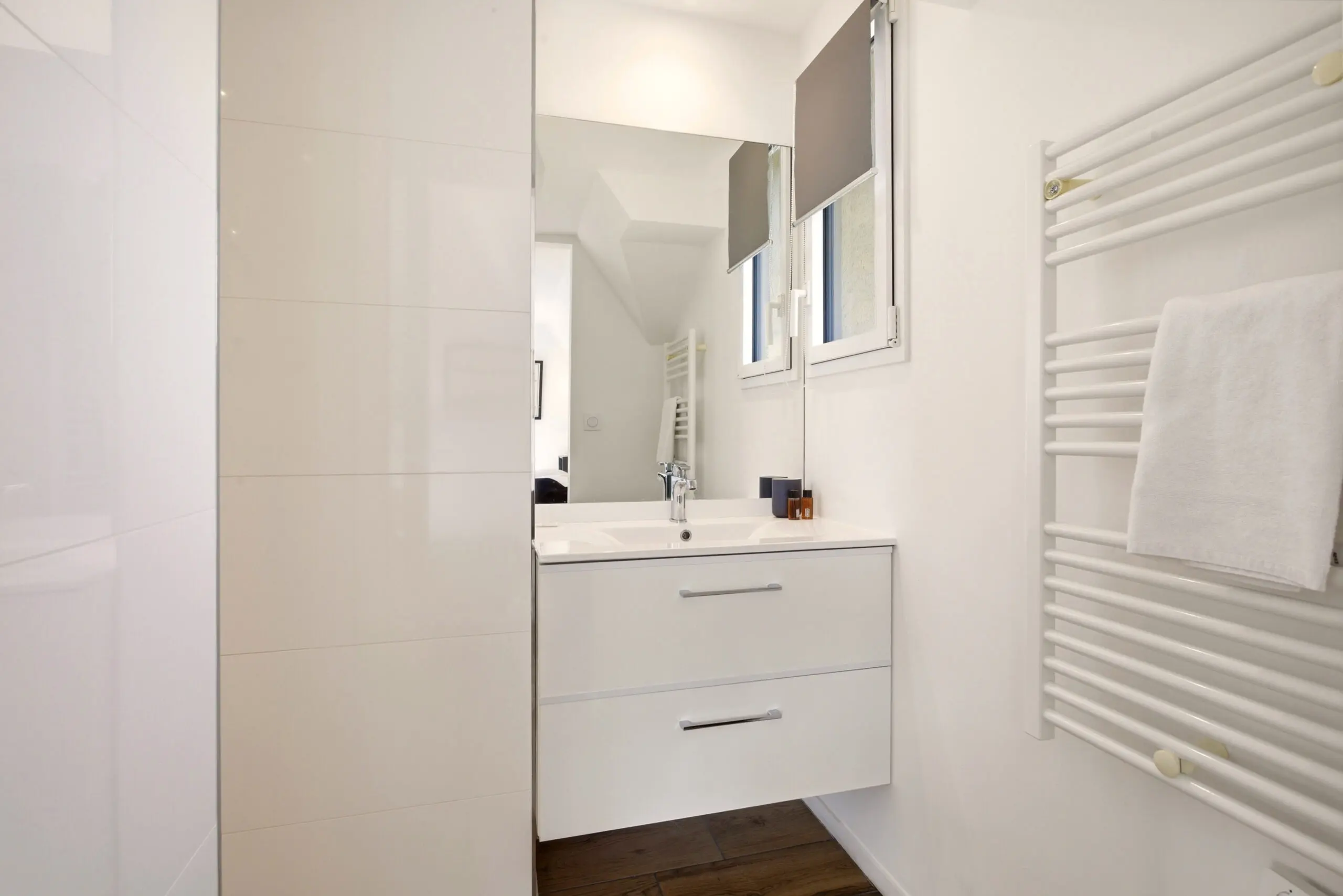 Double vasque blanche et sèche‑serviettes chauffant — salle de bains pratique et raffinée de l’Appartement 56, conciergerie tout‑inclus.